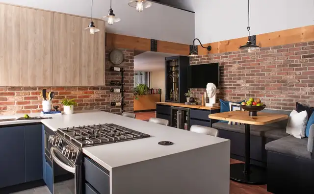 South Loop loft kitchen remodel with a gas cooktop in a white peninsula, a wood booth table and exposed brick and timber