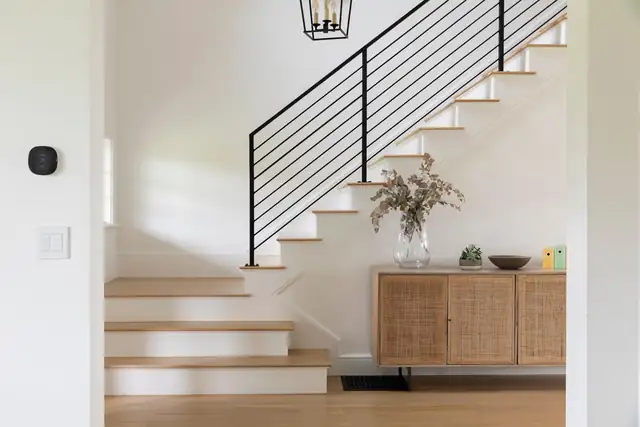 Gold Coast Chicago whole home renovation with white oak stairs, black metal railing and rattan sideboard