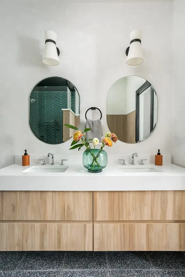 Floating wood double vanity with round mirrors and wall sconces in a South Loop Chicago townhome bathroom remodel