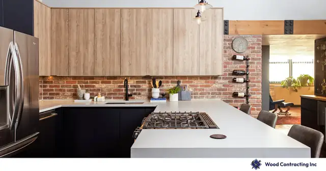 South Loop Chicago loft kitchen remodel with wood-grain upper cabinets, navy lower cabinets, white quartz peninsula and exposed brick wall