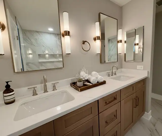 South Loop Chicago condo bathroom remodel with marble-look shower walls, wood vanity, brass mirrors and wall sconces